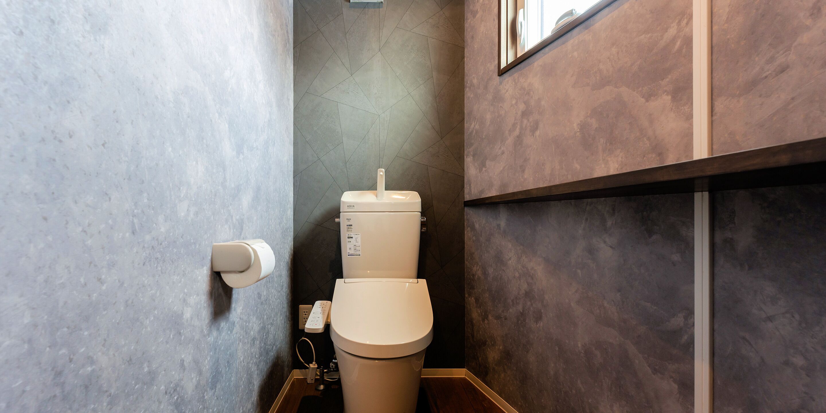 A modern bathroom with a toilet, a hand dryer, and a wall-mounted mirror.