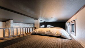 A bedroom with a large bed, a wooden headboard, a carpeted floor, and a window with curtains. - Myoko Onsen cottage Ajisai  (Myoko)