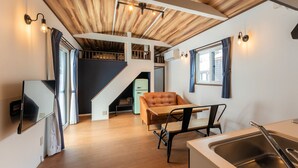 A compact kitchen with a sink, a dining area with a table and chairs, a staircase leading to an upper level, and a television mounted on the wall. - Myoko Onsen cottage Ajisai  (Myoko)