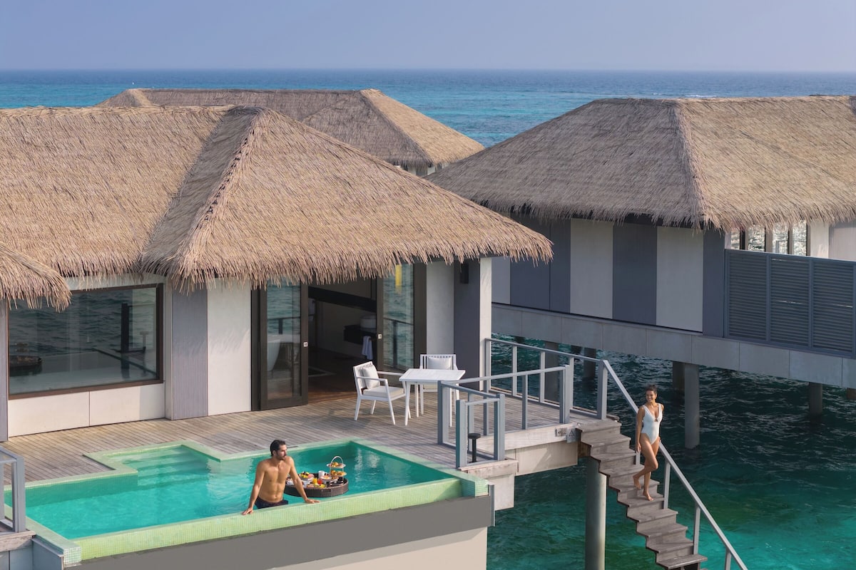 A resort with overwater bungalows, a swimming pool, and a dining area.