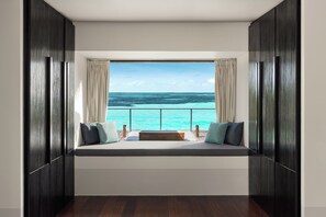A room with a large window overlooking a turquoise sea, a wooden bench with cushions, and dark wooden walls. - Noku Maldives, Vignette Collection by IHG (Kudafunafaru)