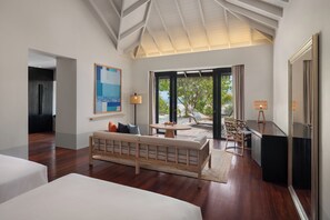 A modern hotel room with a large bed, a sofa, a dining table, and a view of the outdoors.