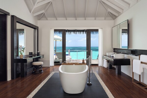 A modern bathroom with a freestanding bathtub, a large mirror, and a view of the ocean. - Noku Maldives, Vignette Collection by IHG (Kudafunafaru)