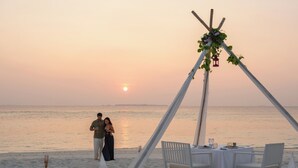 Un paisaje de playa con una carpa y una mesa de comedor.
