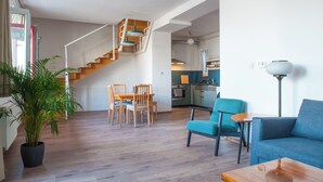 A modern living room with a staircase, a dining area, and a kitchen in the background. - Spacious 2-bedroom 2 story loft near Opera/Andrassy with AC, WiFi (Budapest)