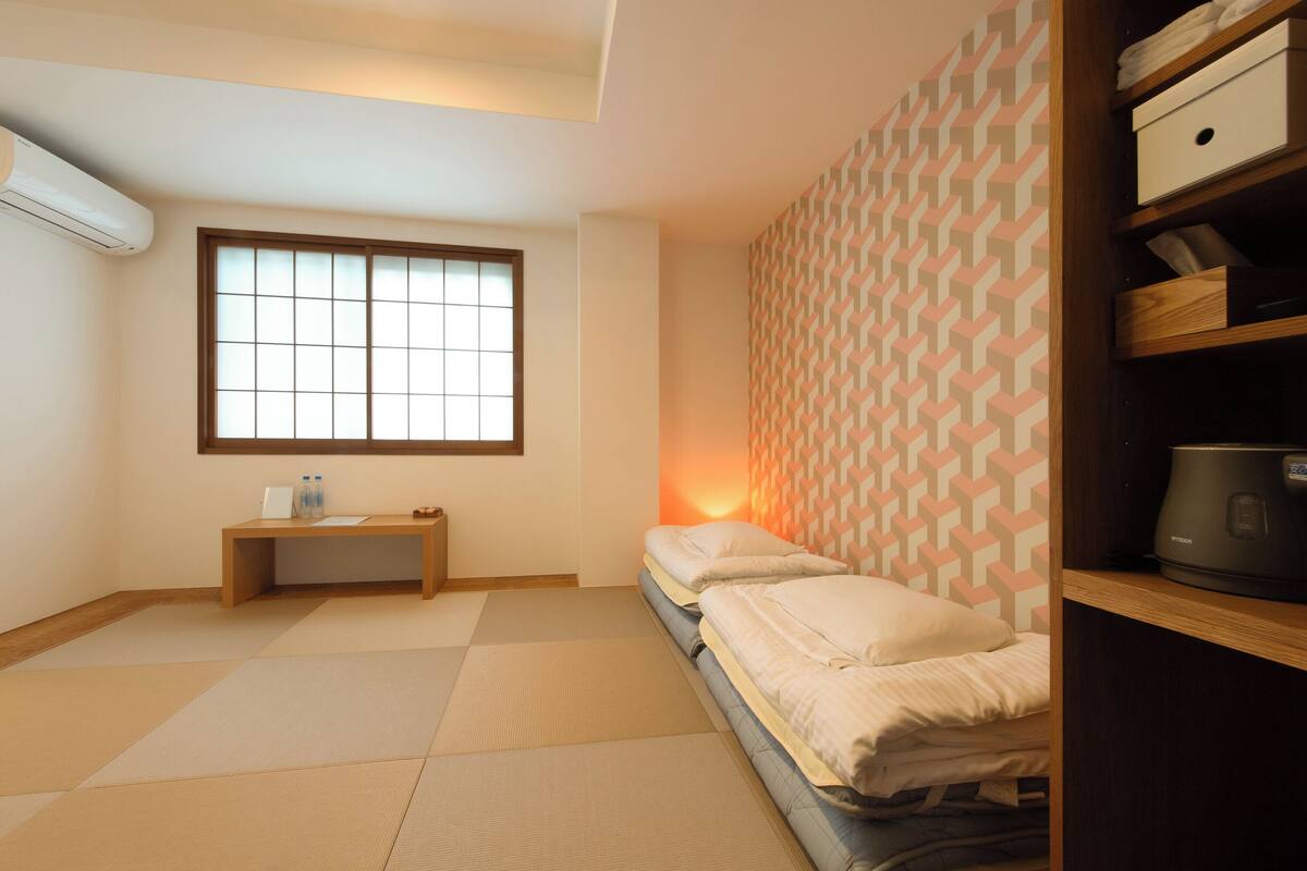 Ein kleiner, ordentlicher Raum mit einem Bett, einem Nachttisch, einem Heizgerät und einem Fenster mit Blick.