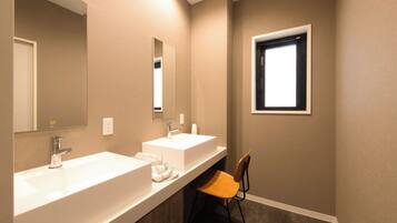 A bathroom with two sinks, a mirror, a window, and a chair.