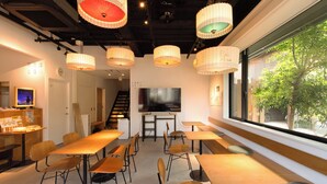 A modern conference room with wooden tables and chairs, a large flat-screen TV, and traditional paper lanterns. - Fushiginayado (Kyoto)