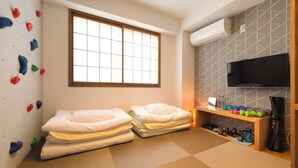 A room with two beds, a climbing wall, a TV, and a shelf with exercise equipment. - Fushiginayado (Kyoto)