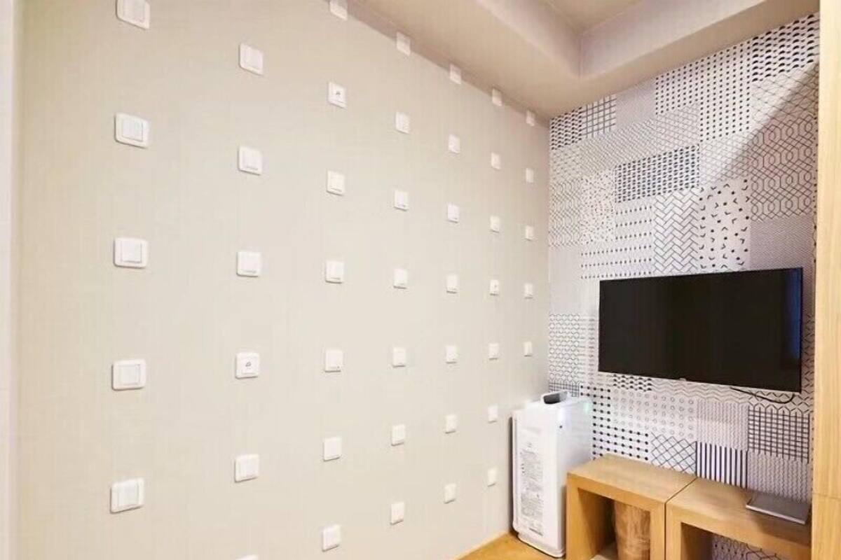 Ein modernes Wohnzimmer mit einem Flachbildfernseher an einer Wand mit Muster, einem Holzkonsolentisch und Einbauleuchten.
