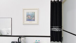 Une chambre d’hôtel avec un tableau encadré au mur, une bouilloire, des bouteilles d’eau et une petite table.