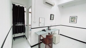 Une chambre d’hôtel équipée d’un bureau, d’une chaise, d’un climatiseur et d’un rideau noir.