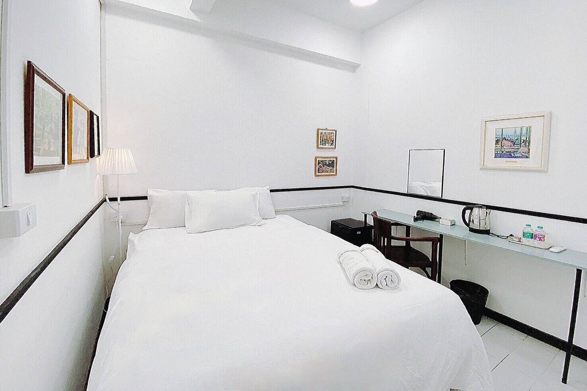 Ein Hotelzimmer mit Bett, Schreibtisch, Stuhl und einem kleinen Tisch mit Wasserkocher und Tassen.