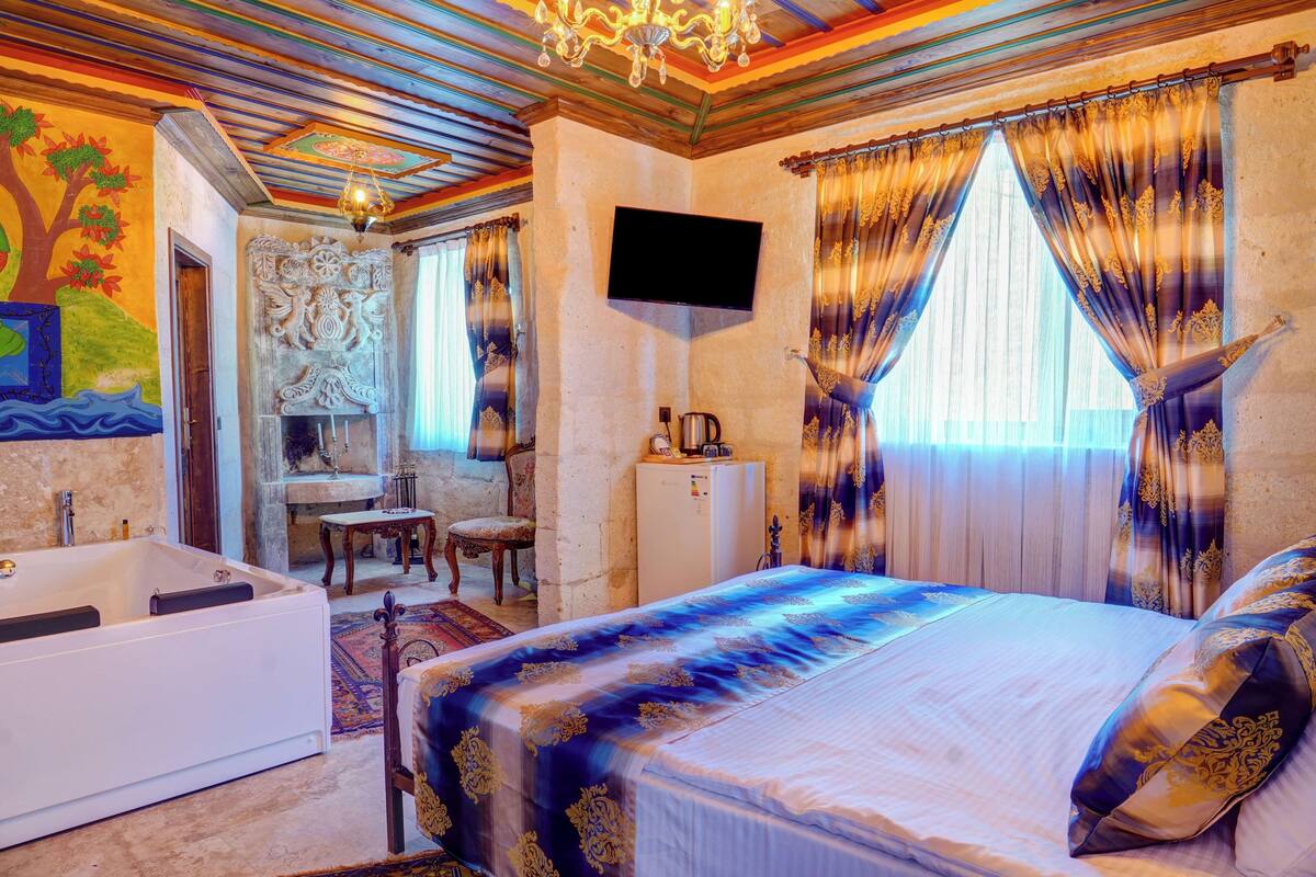 Ein Schlafzimmer mit einem großen Bett, einem Fernseher, einer Badewanne und einem Schreibtisch mit Stuhl.