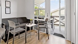 A modern living room with a sofa, chairs, a small table, and a large sliding glass door leading to an outdoor deck. - 6 Person Holiday Park Home in Faaborg (Faaborg)
