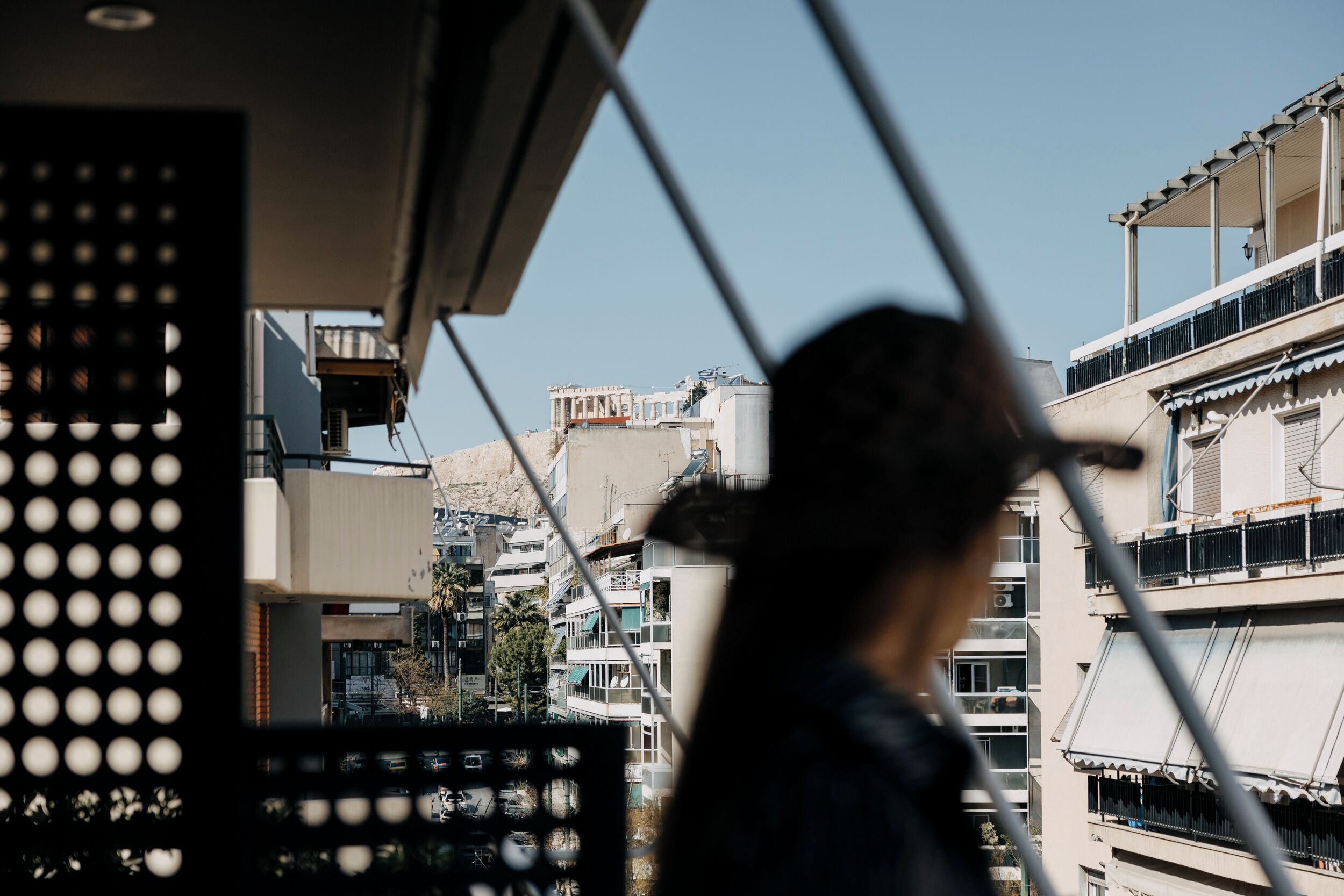 Blick auf eine Stadtlandschaft mit modernen Gebäuden, einem Balkon und einer Person darauf.