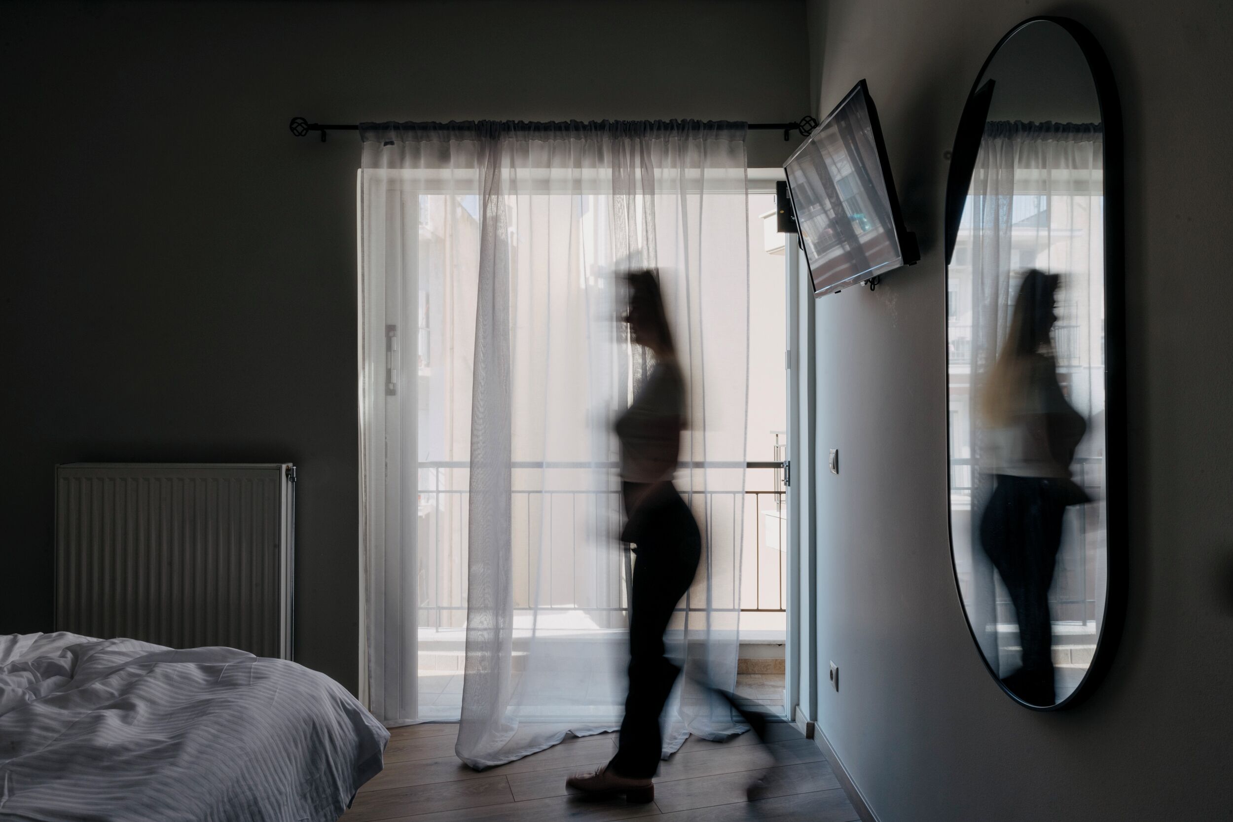 A bedroom with a bed, a large mirror, and a sliding glass door.