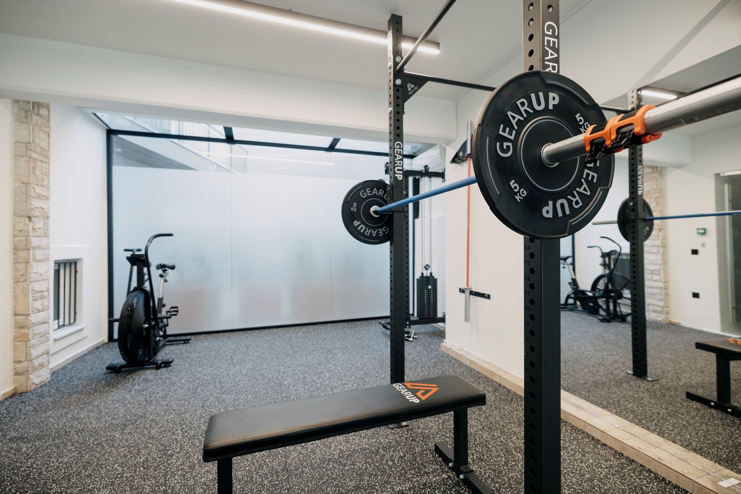 Ett gym med utrustning för styrketräning, en bänk och motionscyklar.
