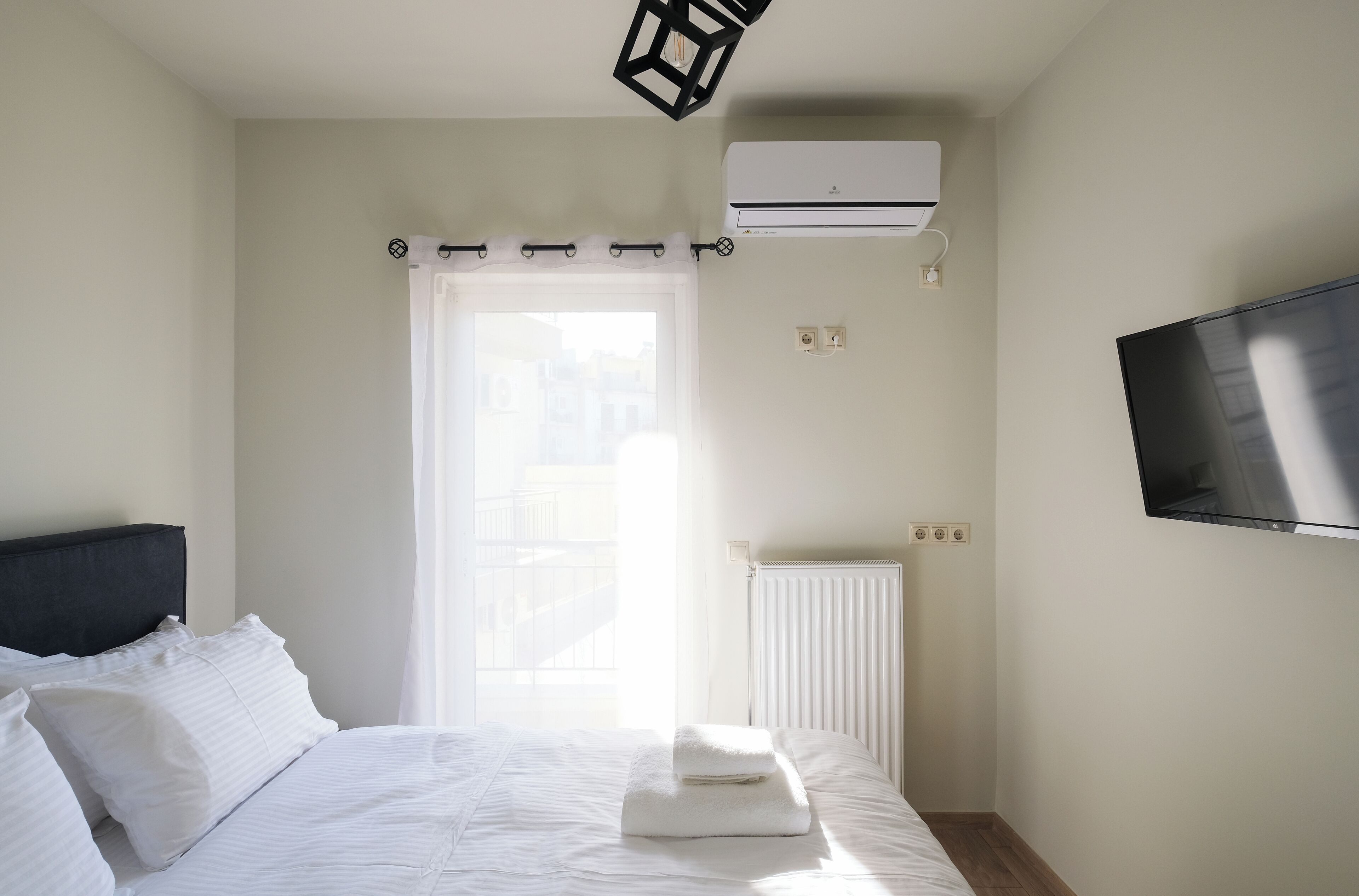 Une chambre d’hôtel équipée d’un lit, d’un téléviseur à écran plat, d’un système de climatisation et d’une fenêtre avec des rideaux.