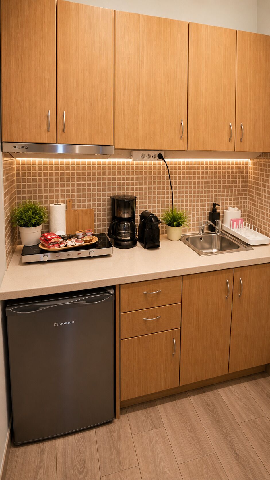 A kitchen with wooden cabinets, a coffee maker, a toaster, a dishwashing unit, and a tiled backsplash.