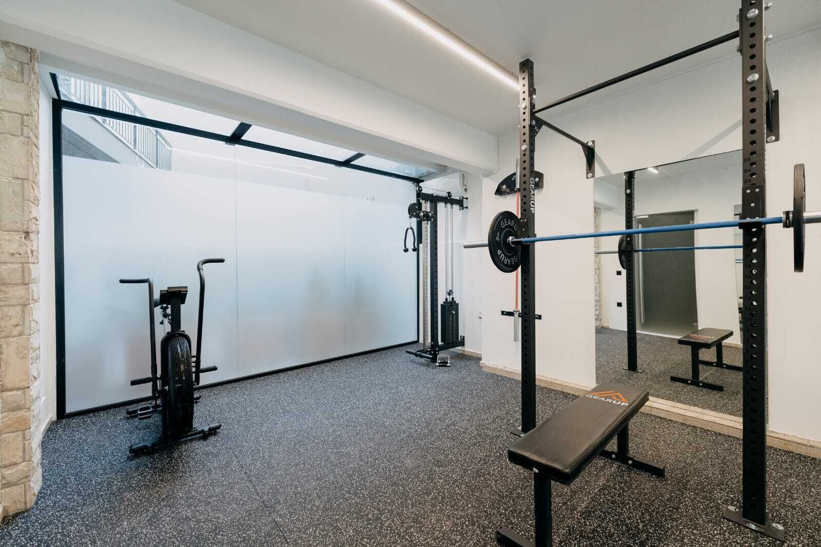 A gym with a pull-up bar, weight bench, and various exercise equipment.