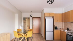 Une cuisine moderne avec des meubles en bois, un réfrigérateur blanc et un coin repas avec des chaises jaunes.