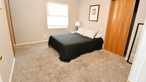 A bedroom with a bed, a window, a nightstand, a lamp, and a door. - 1 Bedroom Apartment Near Notre Dame 1309 5 (South Bend)