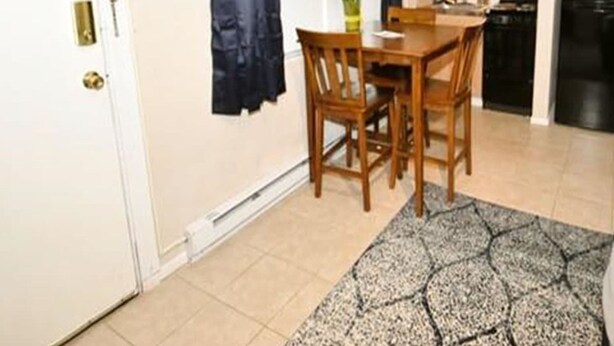 Cocina compacta con comedor, que incluye una mesa pequeña y sillas, un refrigerador y una ventana con cortinas.