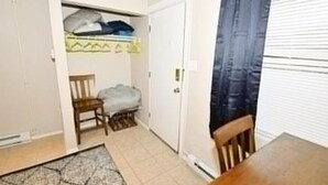 Una habitación pequeña con cama, una silla, una mesita y un armario.
