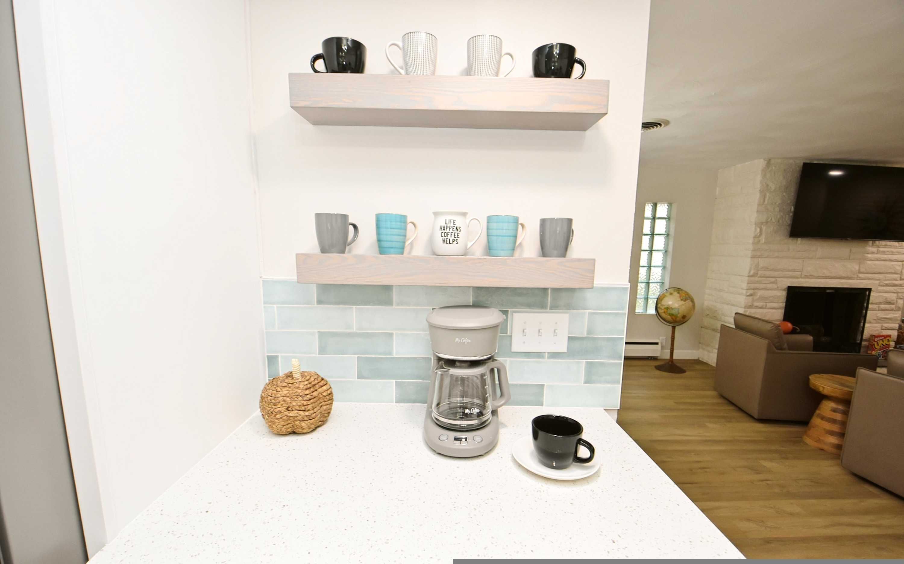 Una cocina moderna con una cafetera, un globo terráqueo y varios tazas en estantes.