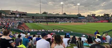 Un estadio de béisbol con una multitud numerosa, campo verde y luces del estadio.