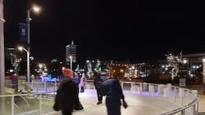 A nighttime pedestrian walkway with metal railings and street lamps.