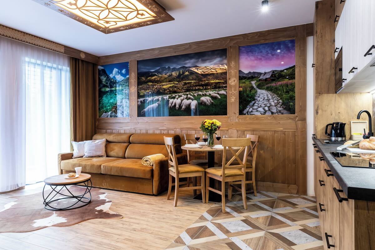 A cozy living room with a sofa, chairs, a coffee table, and a kitchen area with a countertop and sink.
