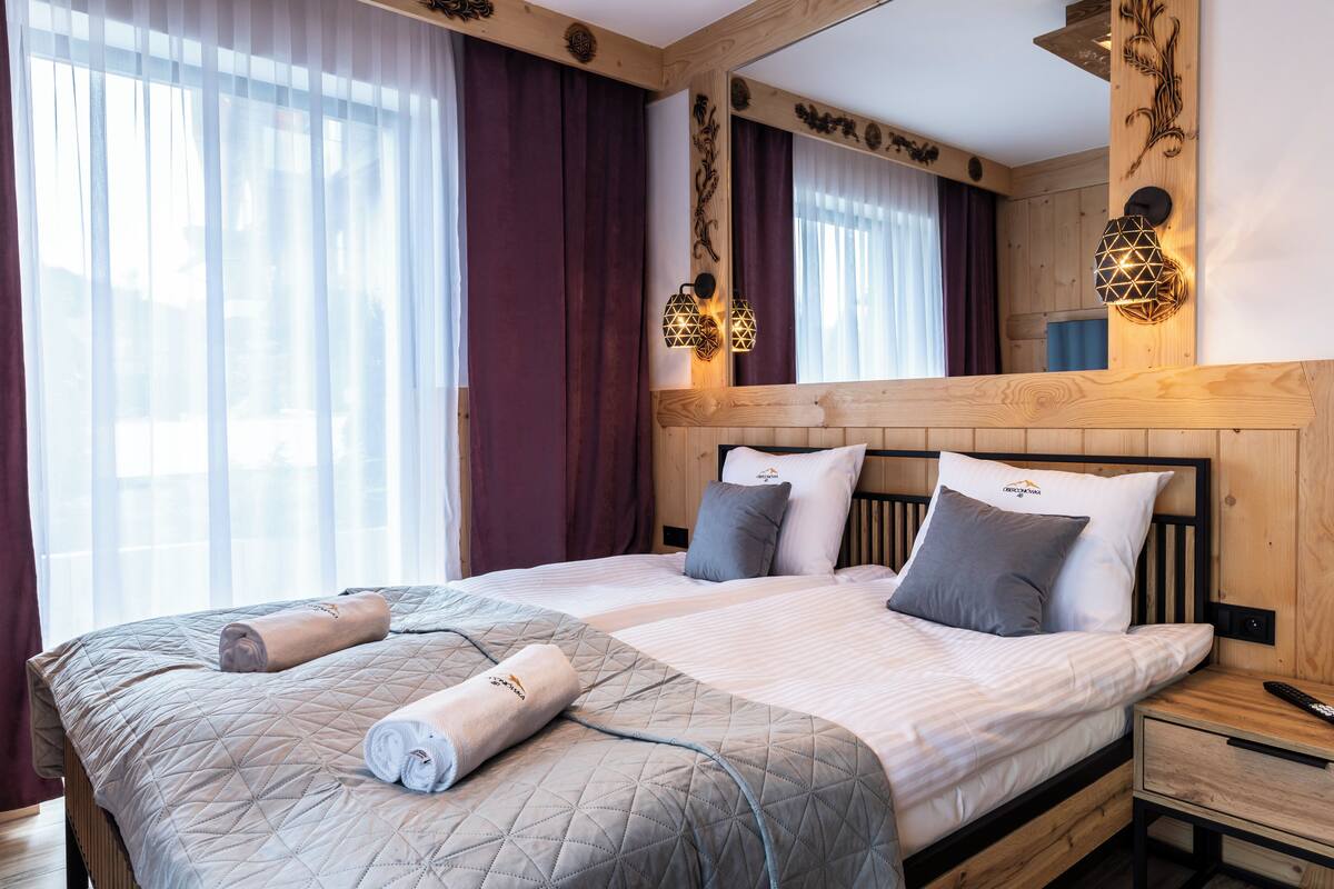 A hotel room with a large bed, wooden headboard, and two bedside tables with lamps.