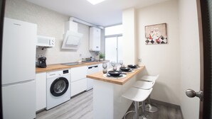A modern kitchen with a washing machine, microwave, and a small dining area with stools. - Molino suites, apt Ronda, two bedrooms en suite in the center of the city  (Ronda)