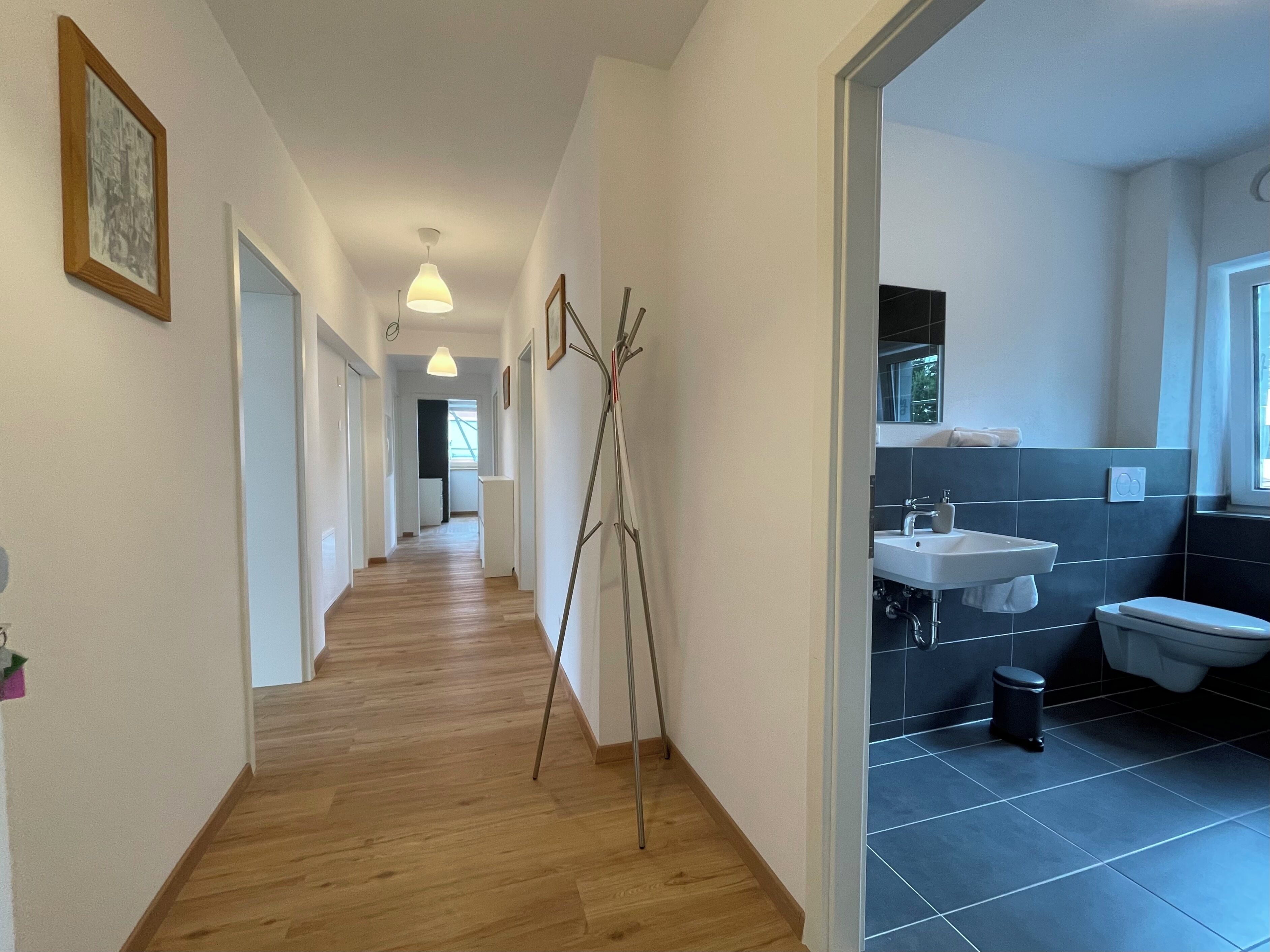 Ein Flur mit Holzboden, einer Stehlampe und einem gerahmten Bild an der Wand.