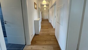 Un couloir doté d’un plancher en bois, de murs blancs et d’une armoire blanche.