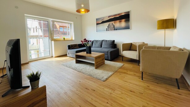 Un salon moderne avec un canapé, des fauteuils, une table basse et un téléviseur.