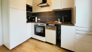 Une cuisine moderne avec des armoires blanches, une cuisinière noire et un plafond en bois.