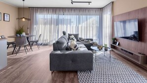 Ein modernes Wohnzimmer mit einer Couch, einem Esstisch und einem an der Wand befestigten Fernseher.