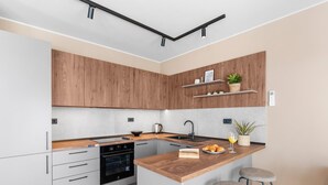 Eine moderne Küche mit Holzausstattung, einem Einbauofen, einer Spüle und einer Bar mit Sitzgelegenheiten.