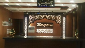 A reception desk with a sign that reads "Reception" and an Arabic sign above it. - Sama AlMisk Hotel (Makkah)