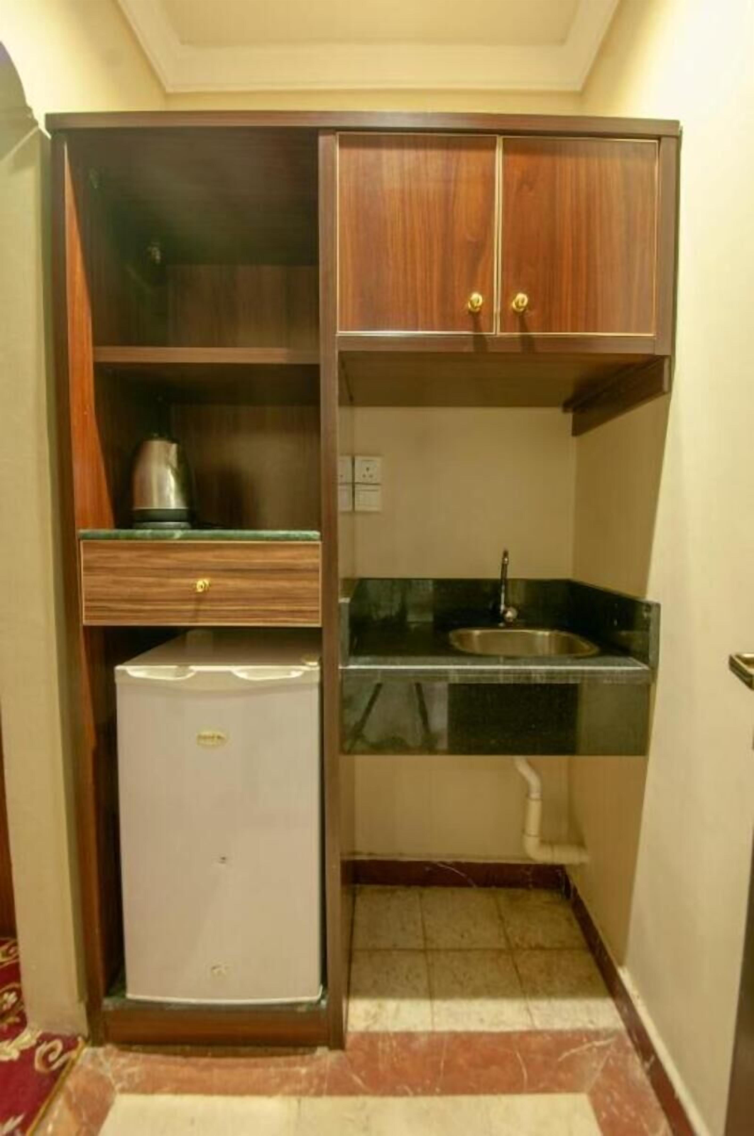 Une cuisine compacte dotée d’un réfrigérateur encastré, d’un évier et d’armoires en bois.
