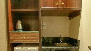 A compact kitchen with a built-in refrigerator, a sink, and wooden cabinets. - Sama AlMisk Hotel (Makkah)