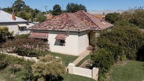 Ein zweigeschossiges Haus mit rotem Ziegeldach, einer kleinen Veranda und einem gepflegten Rasen.