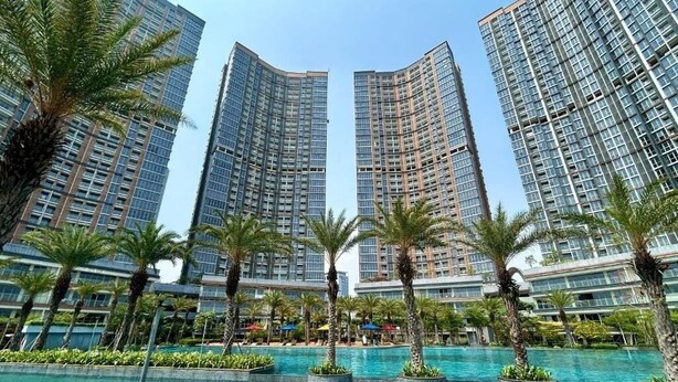 Un hotel moderno con un'ampia area piscina, circondata da palme e grattacieli.