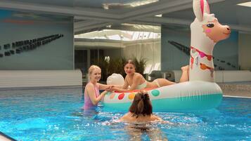 An indoor swimming pool with a large inflatable animal float.