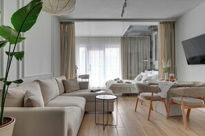 Ein modernes Wohnzimmer mit einer Couch, einem Couchtisch und einem an der Wand befestigten Fernseher.