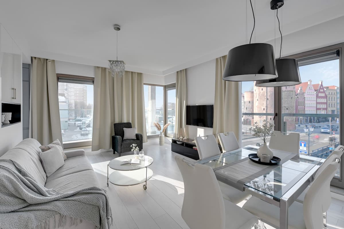A modern living room with a sofa, coffee table, dining table, and TV.