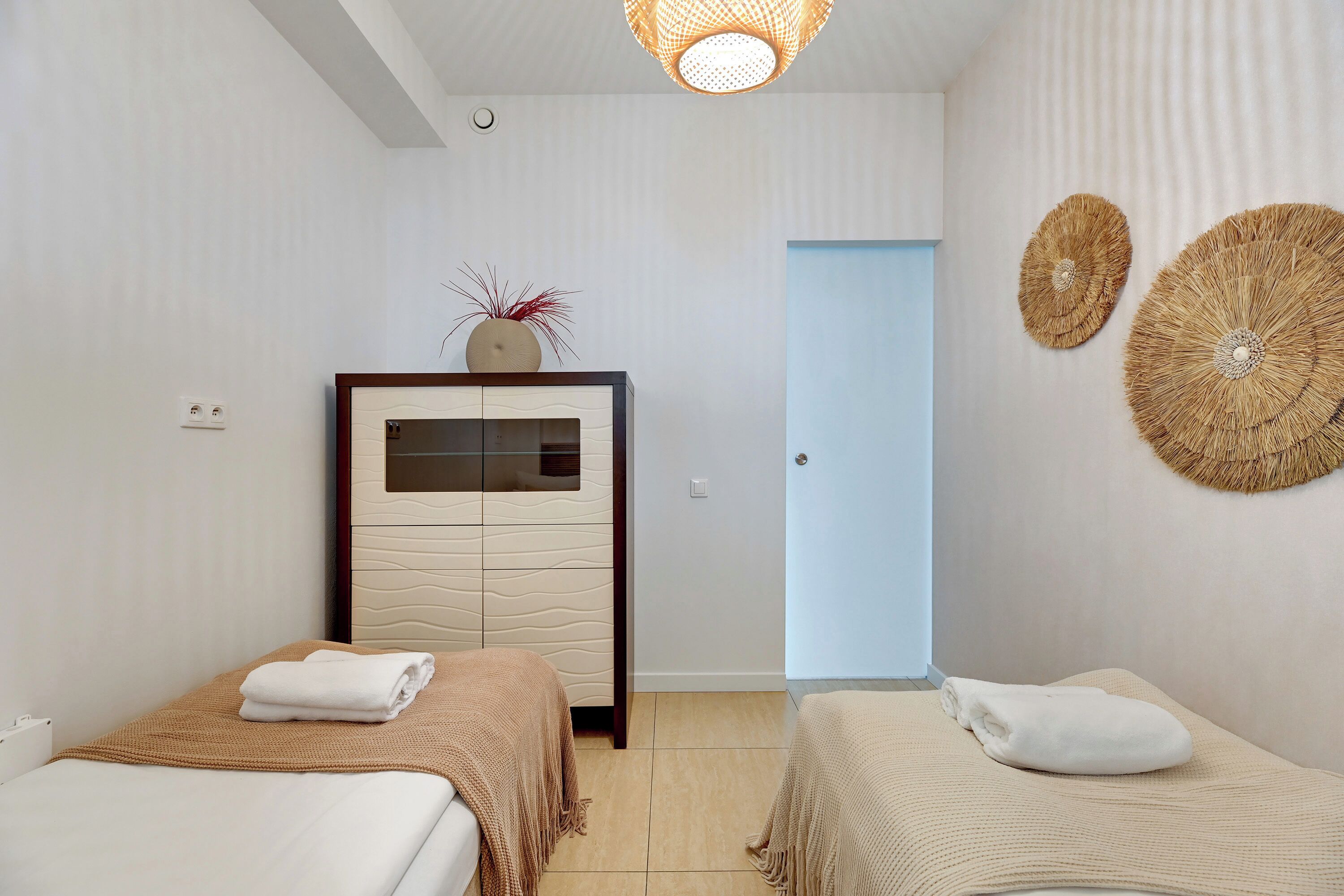 Una habitación de hotel con dos camas, un minibar y una puerta que da a otra habitación.